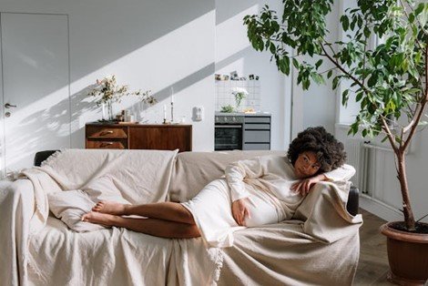 A pregnant woman lying on a sofa in a room full of natural light