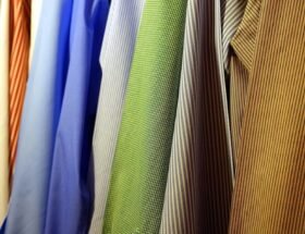 : Neatly hanging dress shirts in various colors and patterns, illustrating organized storage for storing heirloom clothing.