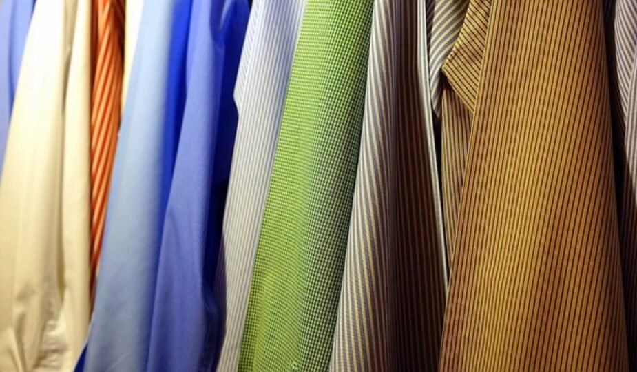 : Neatly hanging dress shirts in various colors and patterns, illustrating organized storage for storing heirloom clothing.