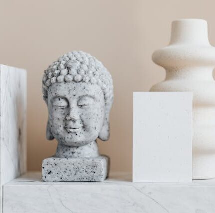 : Luxury interior design pieces featuring a marble Buddha sculpture, a modern white vase, and minimalist geometric blocks, all contributing to an elegant space