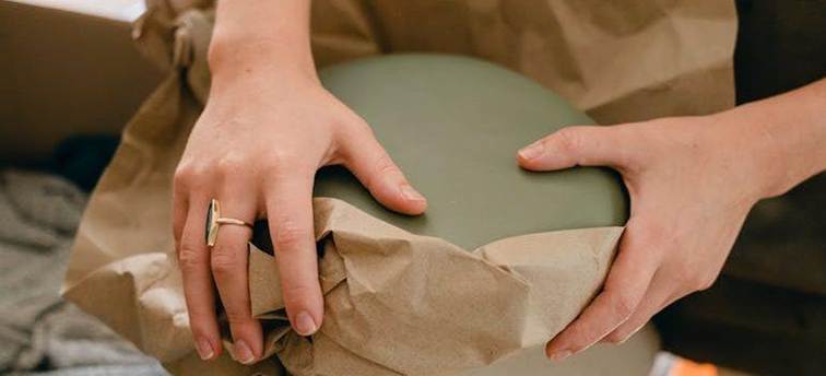 a close-up of hands packing an item using paper