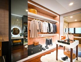 Modern walk-in closet design featuring open shelving, hanging clothes, accessories, a vanity table, and elegant lighting