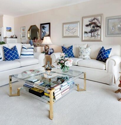 An elegant living room with framed artwork, white sofas, and bold cushions shows how to choose the right art pieces to complete your home design.