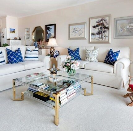 An elegant living room with framed artwork, white sofas, and bold cushions shows how to choose the right art pieces to complete your home design.